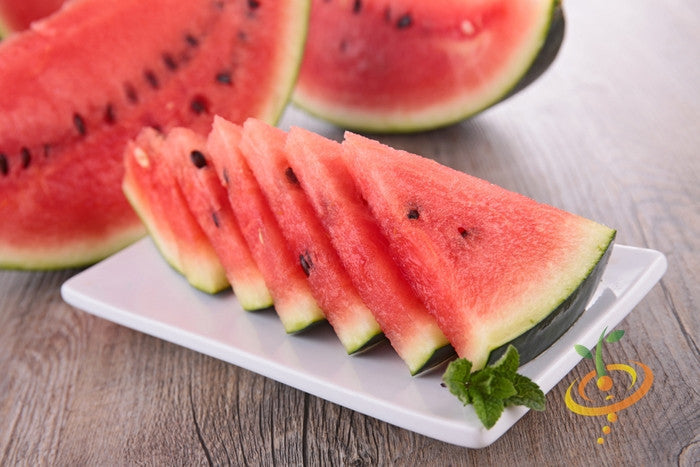 Sliced Florida Giant Watermelon with bright red flesh and dark green rind on a white plate with mint garnish