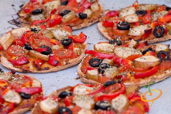Red Pear Tomato Seeds | Mini pizzas topped with red pear tomato slices, red bell peppers, black olives, and herbs on a baking tray